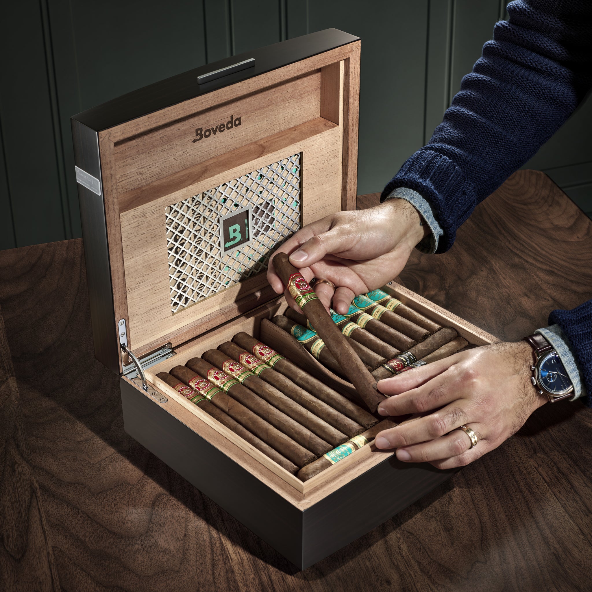 Boveda Humidor open with hands holding a cigar