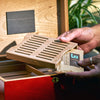 Person placing a Boveda pack into a Boveda wood holder for humidors.