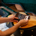 Person placing a Boveda 49% RH into the Boveda fabric holder before placing it into a guitar case with the guitar.
