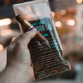 Persons hand holding a cigar and a small humidor bag.